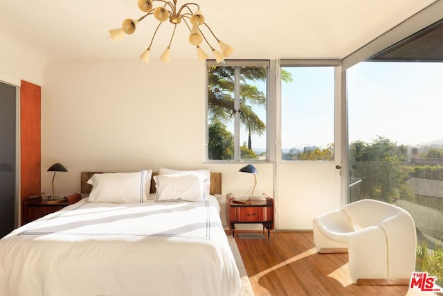 bedroom with multiple windows, hardwood / wood-style floors, and a chandelier