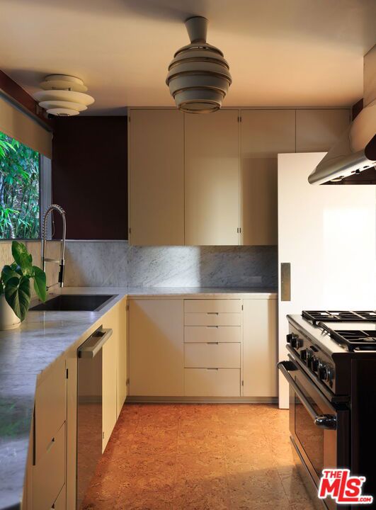 kitchen with tasteful backsplash, appliances with stainless steel finishes, extractor fan, and sink