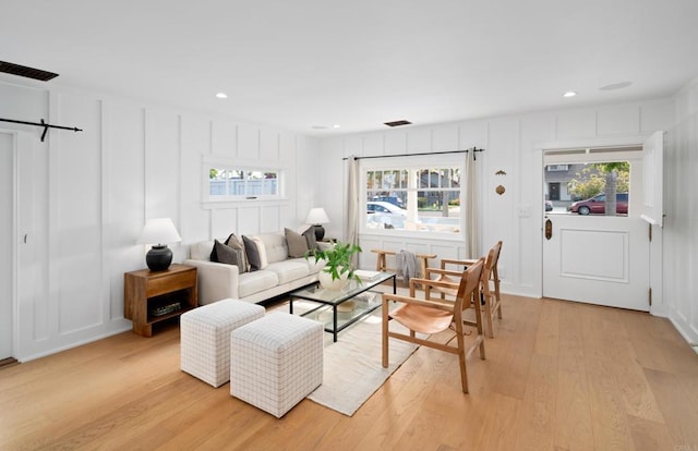 living room with a wealth of natural light, light hardwood / wood-style flooring, and a barn door