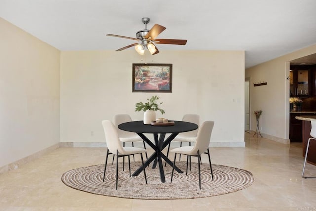 dining area with a ceiling fan and baseboards