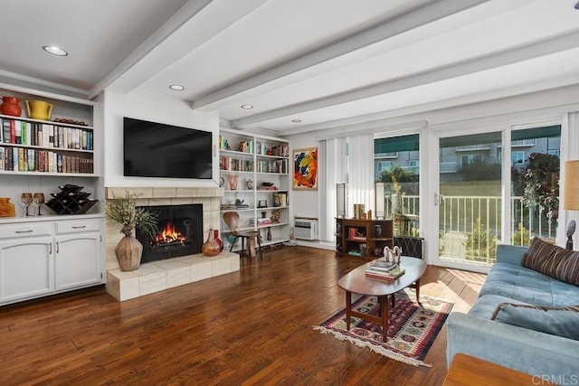 living area featuring built in shelves, recessed lighting, a tile fireplace, beamed ceiling, and hardwood / wood-style flooring