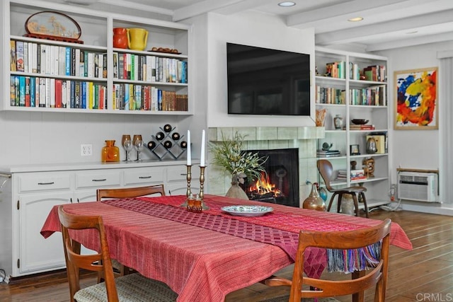 living area with a wall unit AC, recessed lighting, wood finished floors, beamed ceiling, and a lit fireplace