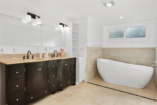 bathroom featuring double vanity, a freestanding tub, tile patterned flooring, and a sink