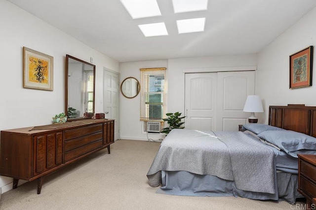 bedroom with a skylight, a closet, light carpet, and baseboards