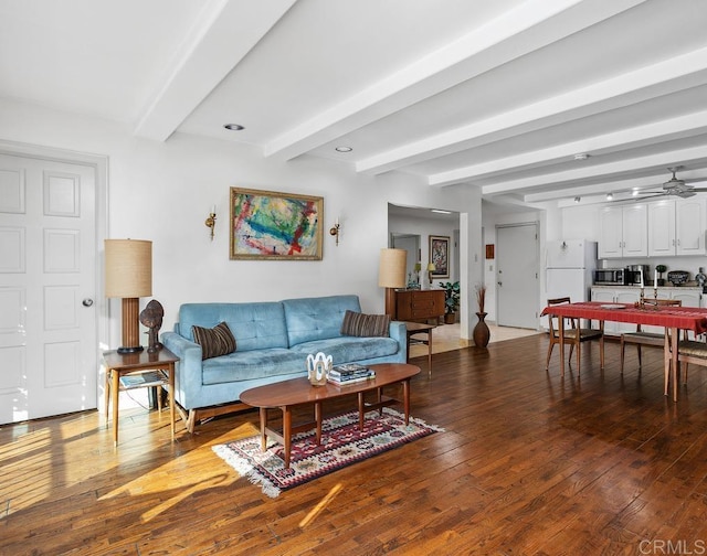 living area with ceiling fan, hardwood / wood-style floors, and beamed ceiling