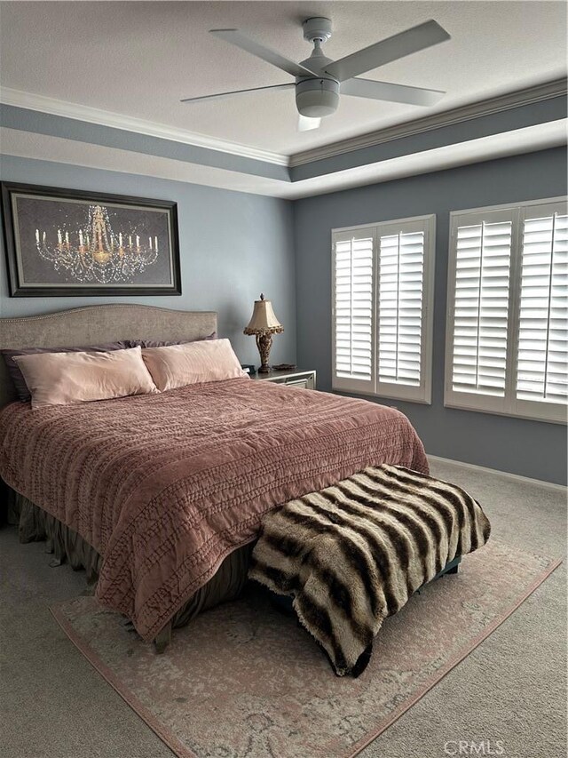 bedroom featuring ornamental molding, a raised ceiling, ceiling fan, and carpet