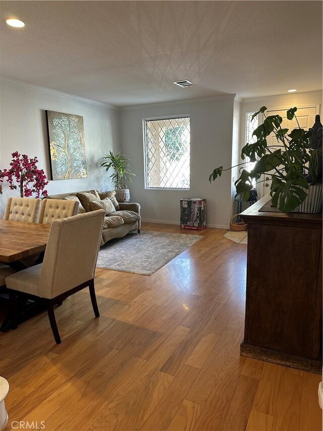 living room featuring crown molding, a textured ceiling, and light hardwood / wood-style floors