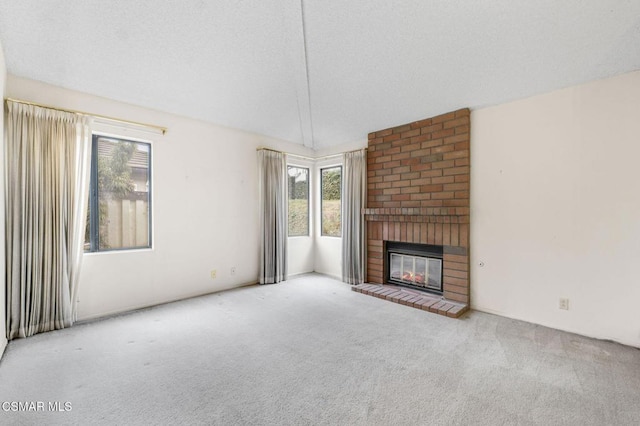 unfurnished living room with light colored carpet, a fireplace, and a textured ceiling