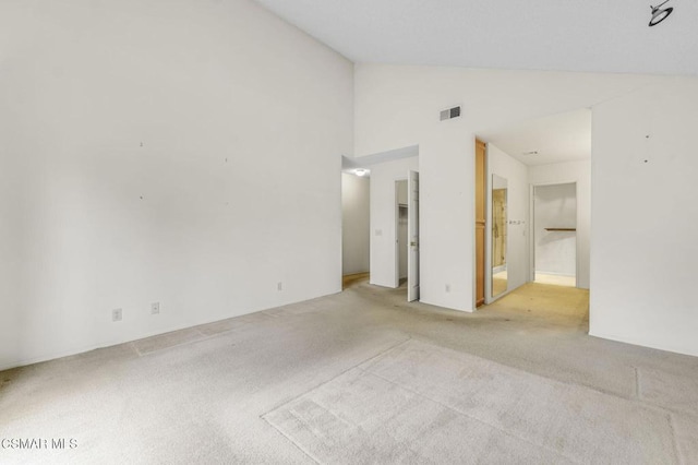 spare room with light carpet and high vaulted ceiling