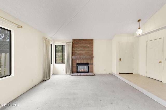 unfurnished living room with a fireplace, vaulted ceiling, and carpet flooring