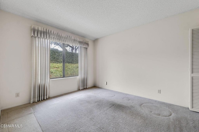 unfurnished room with a textured ceiling and carpet flooring