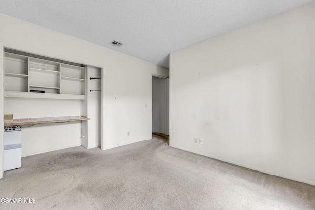 unfurnished bedroom with light carpet, a closet, and a textured ceiling