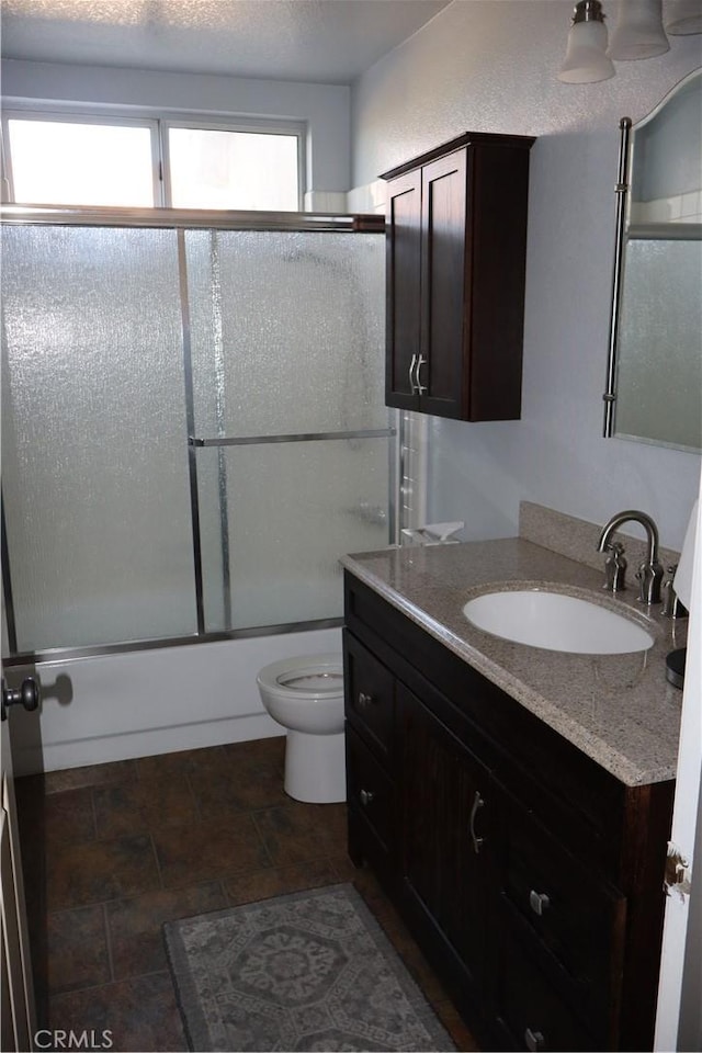 full bathroom with bath / shower combo with glass door, vanity, a textured ceiling, and toilet