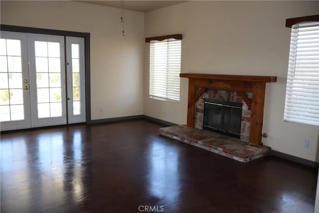 unfurnished living room featuring dark hardwood / wood-style floors, a stone fireplace, and french doors