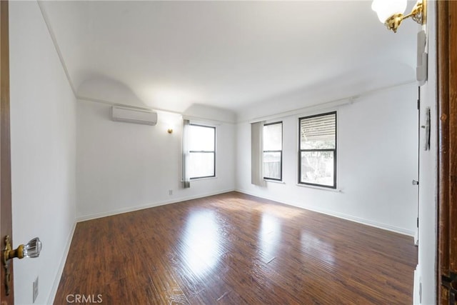 spare room featuring dark wood-type flooring and a wall unit AC