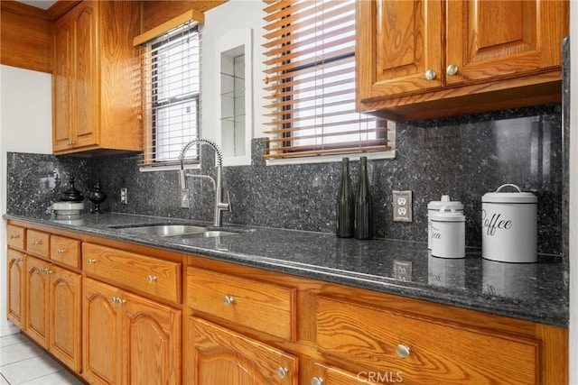 kitchen featuring light tile patterned flooring, sink, decorative backsplash, and dark stone countertops