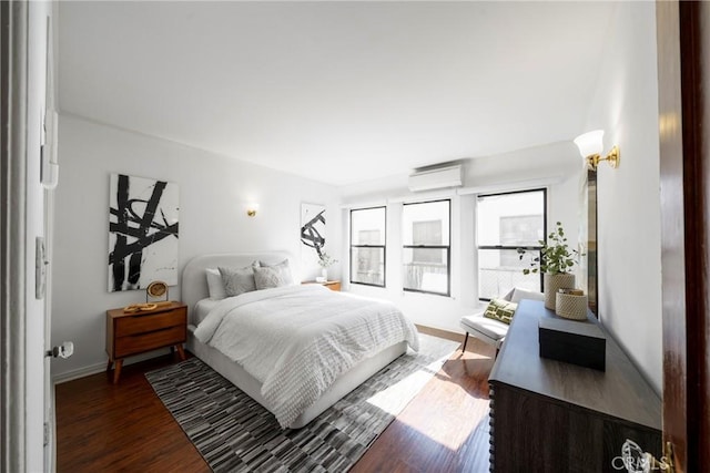 bedroom with a wall mounted air conditioner and dark hardwood / wood-style flooring