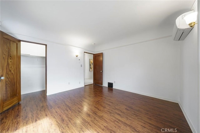 unfurnished bedroom with a closet, dark hardwood / wood-style flooring, and a wall unit AC