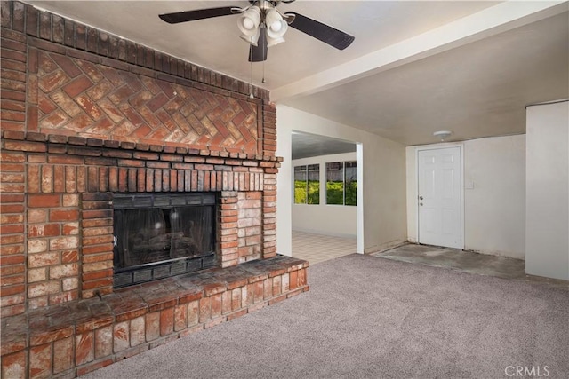 unfurnished living room featuring beamed ceiling, ceiling fan, carpet, and a fireplace