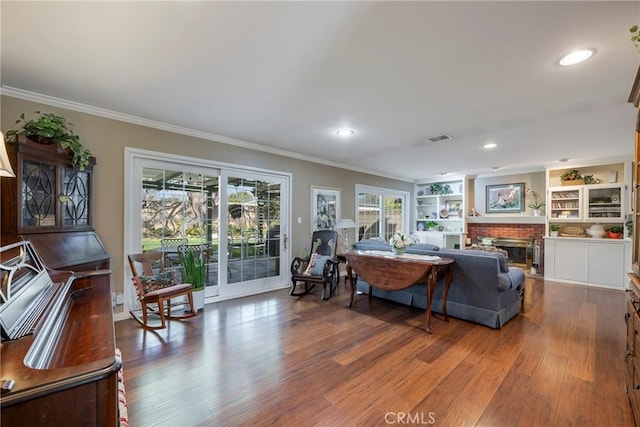 living room featuring hardwood / wood-style flooring, ornamental molding, and a fireplace