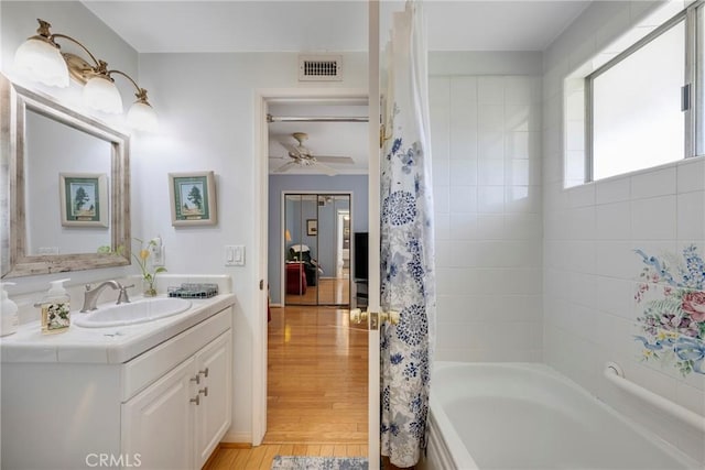 bathroom with shower / bath combination with curtain, ceiling fan, wood-type flooring, and vanity