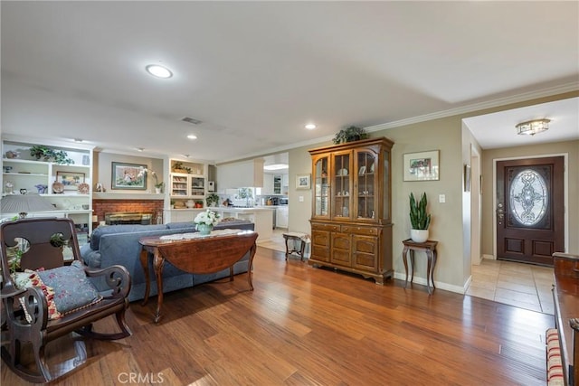 living room featuring crown molding, a fireplace, and light hardwood / wood-style floors