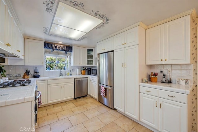 kitchen featuring stainless steel appliances, white cabinetry, sink, and tile counters