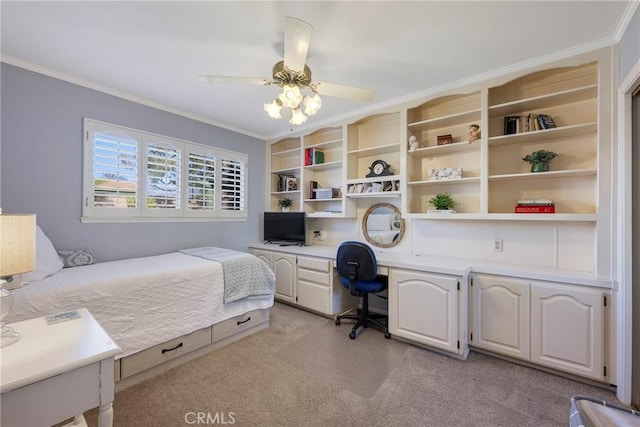 carpeted bedroom featuring built in desk, ornamental molding, and ceiling fan