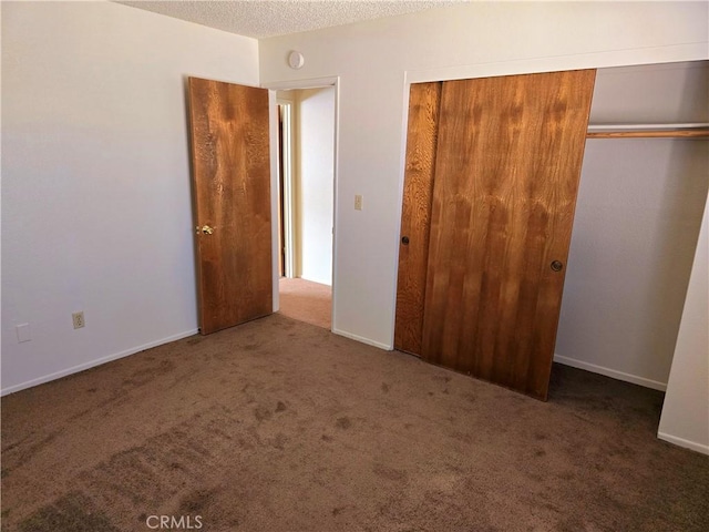 unfurnished bedroom featuring a textured ceiling, a closet, carpet, and baseboards