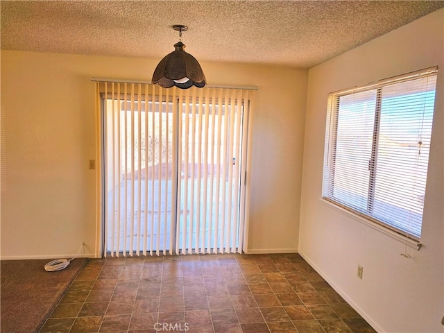 unfurnished dining area featuring a textured ceiling and baseboards