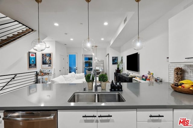 kitchen with stainless steel dishwasher, decorative light fixtures, sink, and white cabinets