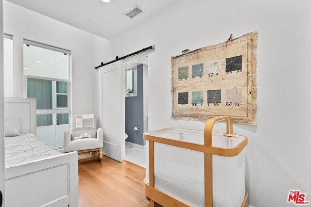 bedroom with a barn door and light hardwood / wood-style flooring