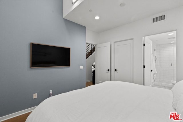 bedroom featuring connected bathroom and dark wood-type flooring