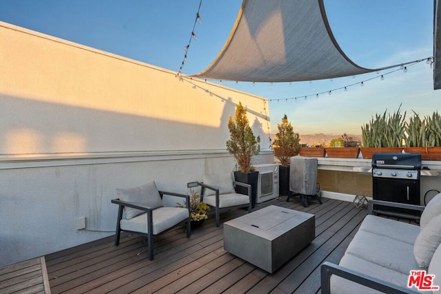 deck at dusk featuring a grill