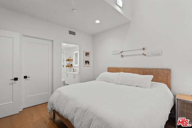 bedroom featuring ensuite bathroom and light hardwood / wood-style floors