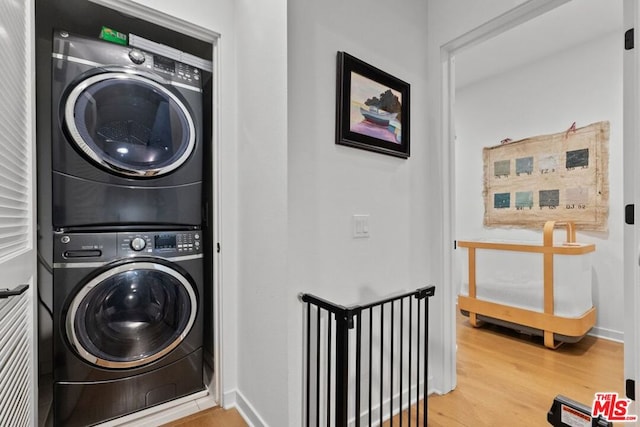 laundry area with hardwood / wood-style flooring and stacked washer and clothes dryer