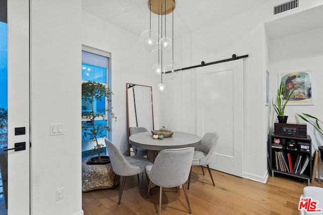 dining space featuring light hardwood / wood-style flooring and a barn door