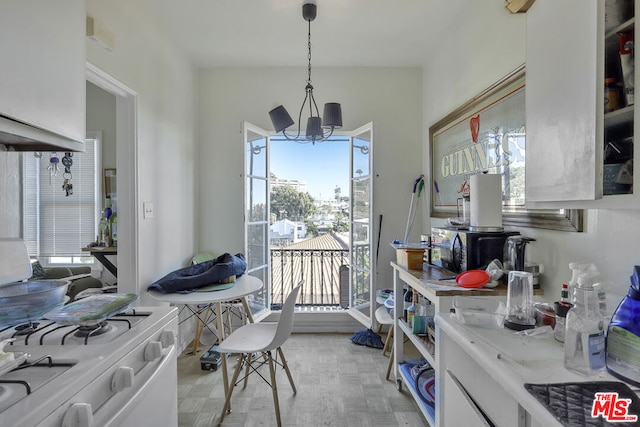 interior space with an inviting chandelier, decorative light fixtures, light parquet flooring, and white cabinets