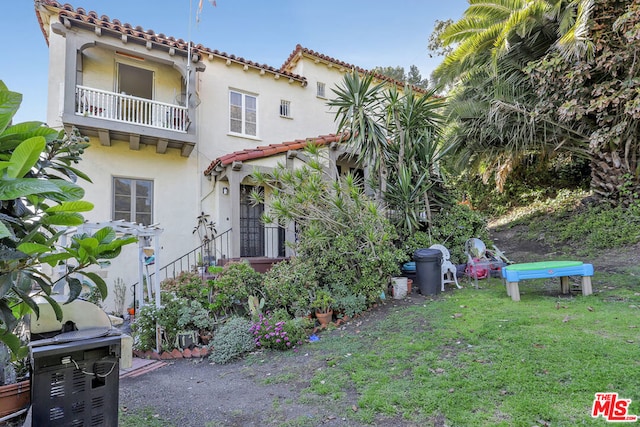 view of front of house with a balcony and a front yard