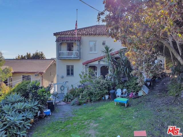 back of property with a balcony and a lawn