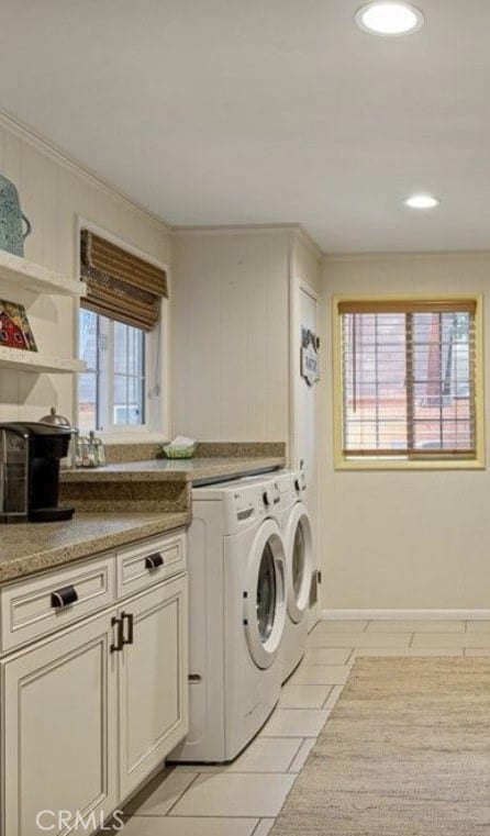 laundry area with a healthy amount of sunlight, cabinets, washing machine and clothes dryer, and light tile patterned flooring