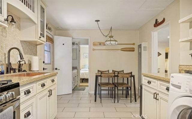 kitchen with stainless steel range with gas cooktop, washer / clothes dryer, light stone countertops, and sink