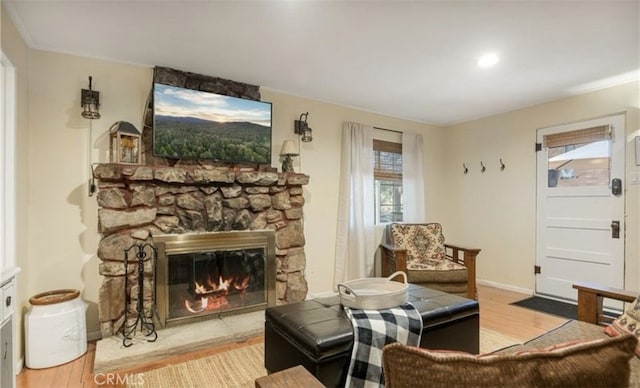 living area with a stone fireplace and light wood-type flooring