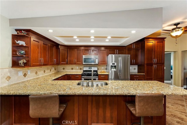 kitchen featuring decorative backsplash, stainless steel appliances, kitchen peninsula, and a raised ceiling