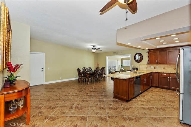 kitchen with sink, appliances with stainless steel finishes, backsplash, light stone countertops, and kitchen peninsula