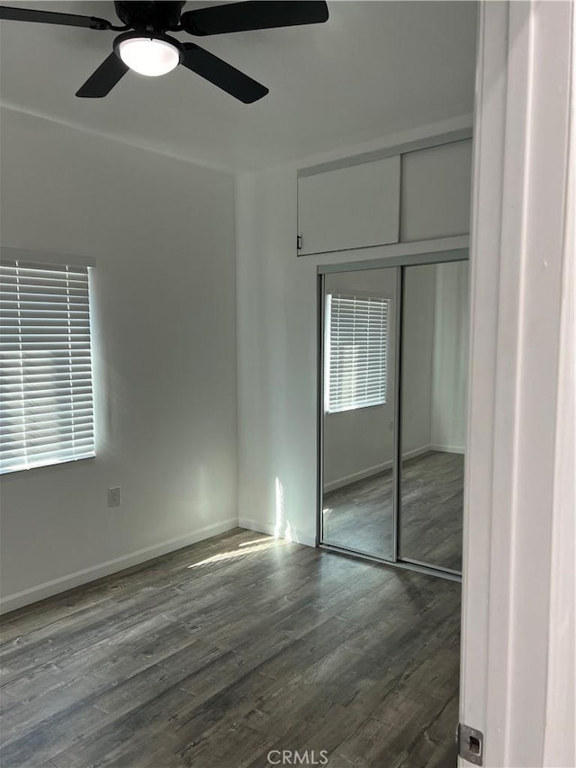 unfurnished bedroom featuring dark hardwood / wood-style floors, ceiling fan, and a closet