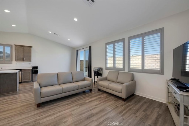 living room featuring vaulted ceiling, wood-type flooring, and a healthy amount of sunlight