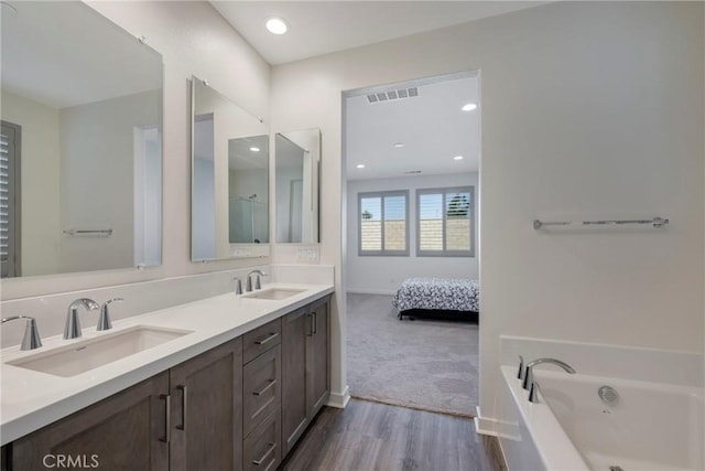 bathroom featuring vanity, a bath, and wood-type flooring