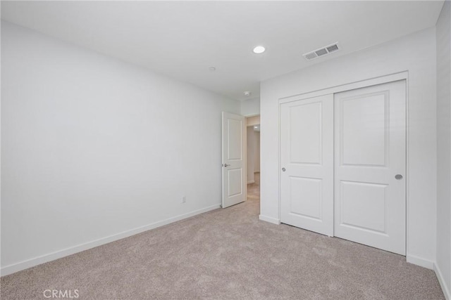 unfurnished bedroom featuring light carpet and a closet