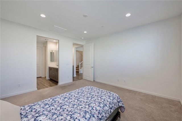 bedroom with ensuite bathroom and light carpet